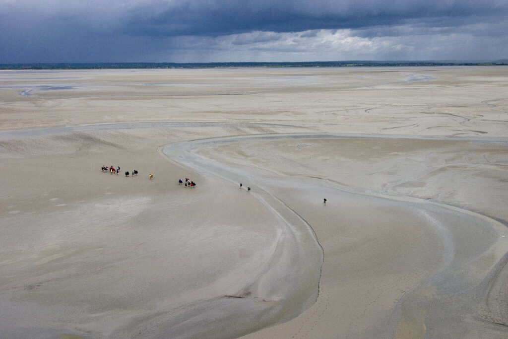 Walkers at low tide in the Bay of Mont Saint Michel in Normandy
